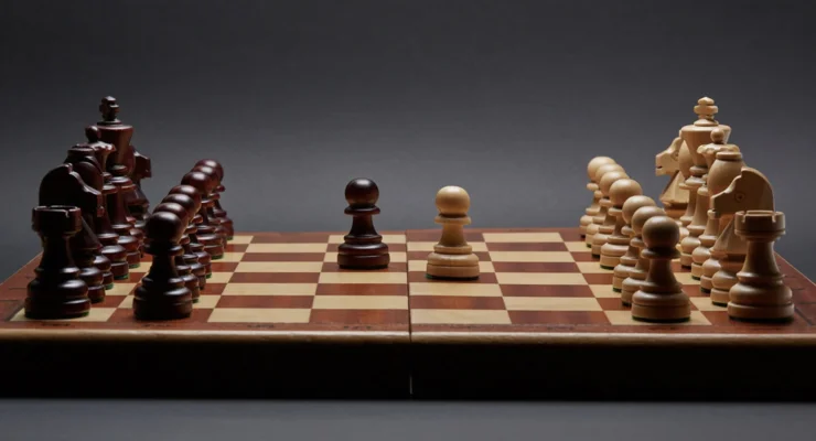 Side view of a chess board with white pieces on the right-hand side and black pieces on the left-hand side.