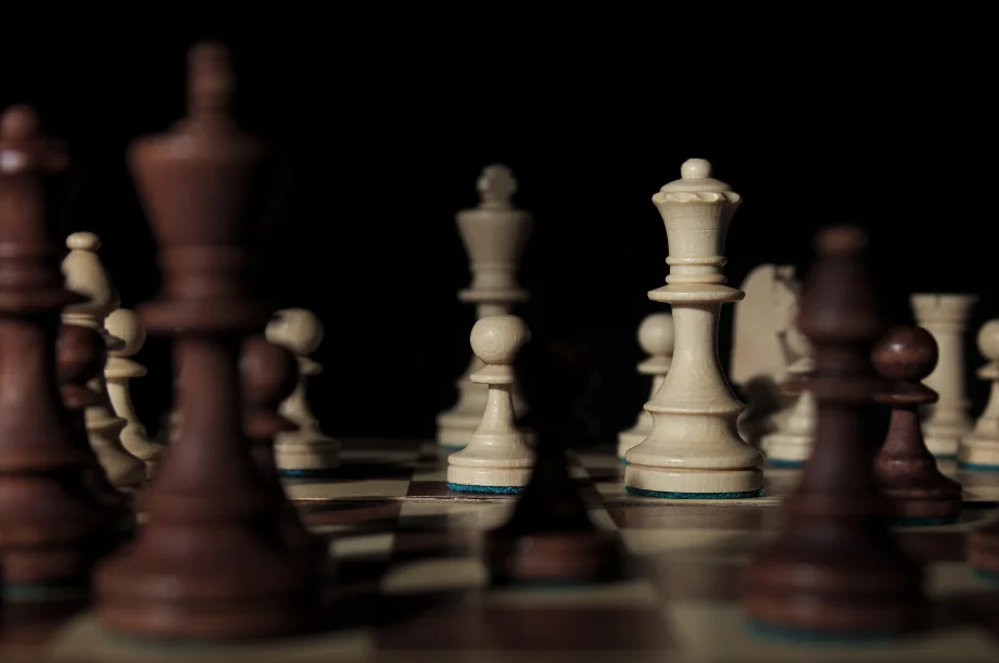 A closeup view of chess pieces in dim lighting.